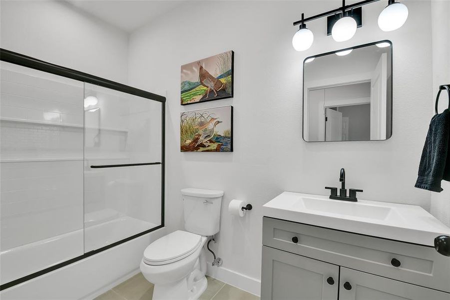 Full bathroom featuring vanity, toilet, combined bath / shower with glass door, and tile patterned floors