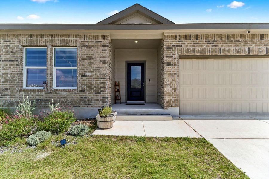 An inviting brick facade welcomes with a convenient attached garage and neatly landscaped entryway.