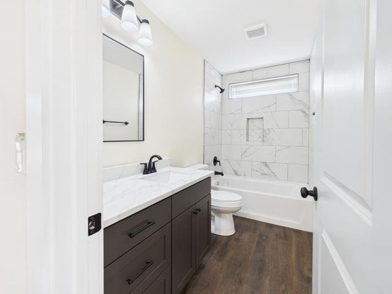 Before photo featuring vanity, shower / tub combination, and dark wood-type flooring
