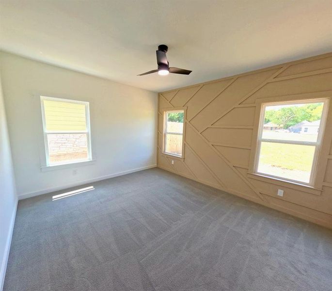 Unfurnished room with carpet, a ceiling fan, and a decorative wall Unfurnished room with carpet, a ceiling fan, and a decorative wall