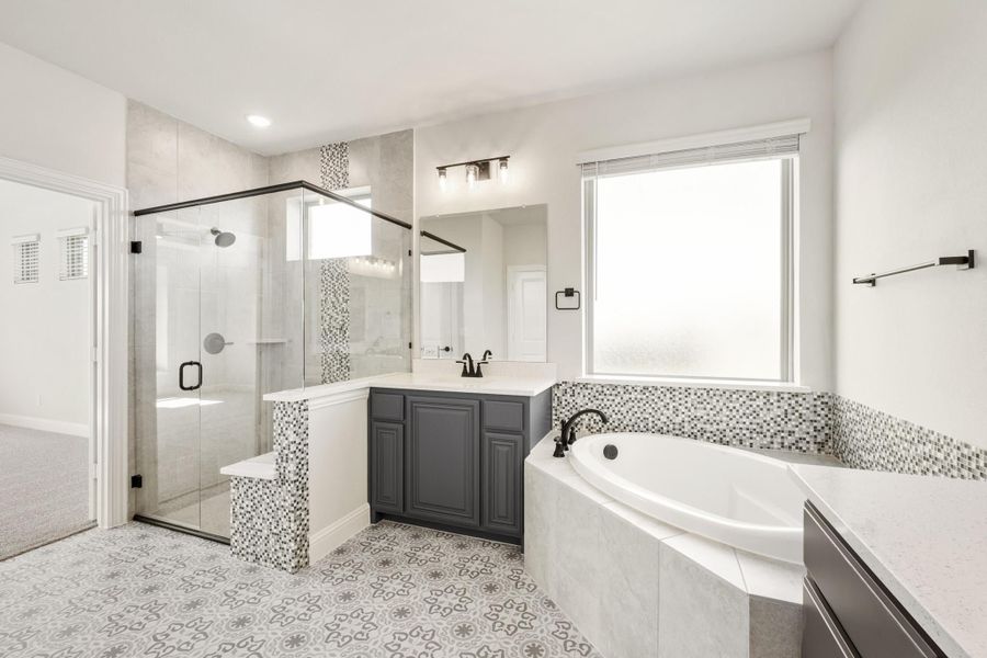Master bathroom with glass walk-in shower, soaking tub, gray vanity, and patterned tile floors Master bathroom with glass walk-in shower, soaking tub, gray vanity, and patterned tile floors