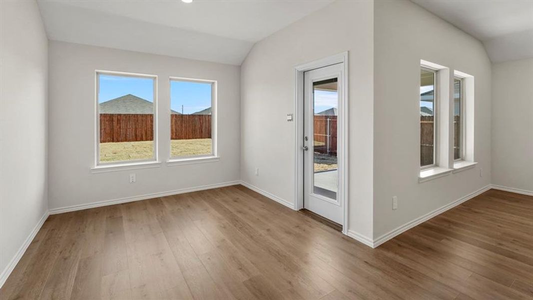 Spacious room featuring wood-finish flooring, white baseboards, and neutral wall tones