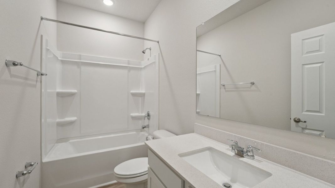 Elegant quartz surfaces and seamless wood floors elevate the bathroom in this Palm Coast residence.