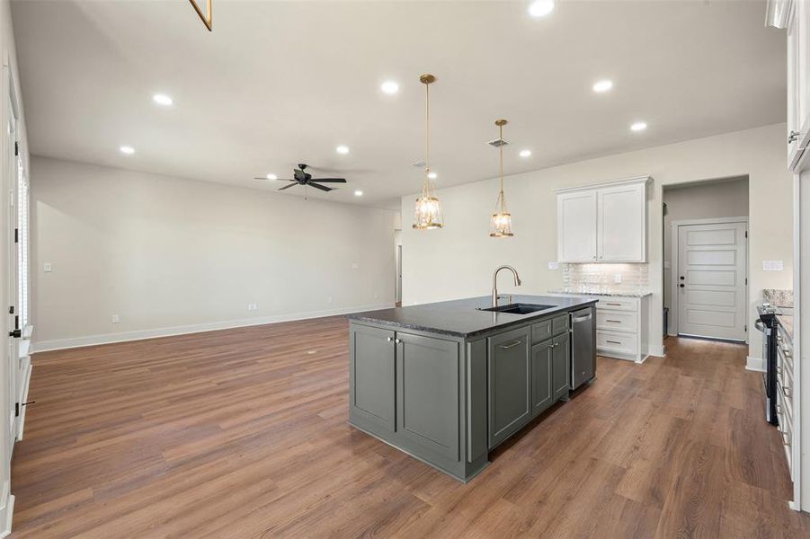 Kitchen with open floor plan, gray cabinets, white cabinetry, pendant lighting, and ceiling fan