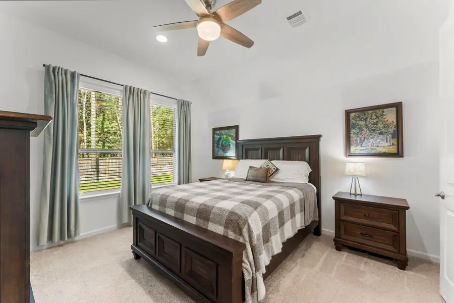 The primary suite hosts large windows giving tons of natural light and views of the backyard and green space beyond.