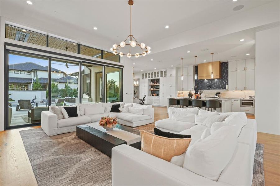 Living area featuring light wood-type flooring, recessed lighting, a chandelier, and floor to ceiling windows Living area featuring light wood-type flooring, recessed lighting, a chandelier, and floor to ceiling windows