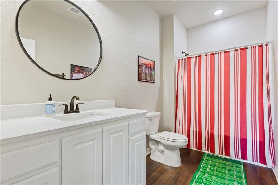 Full bath featuring dark wood finished floors, vanity, and shower / tub combo
