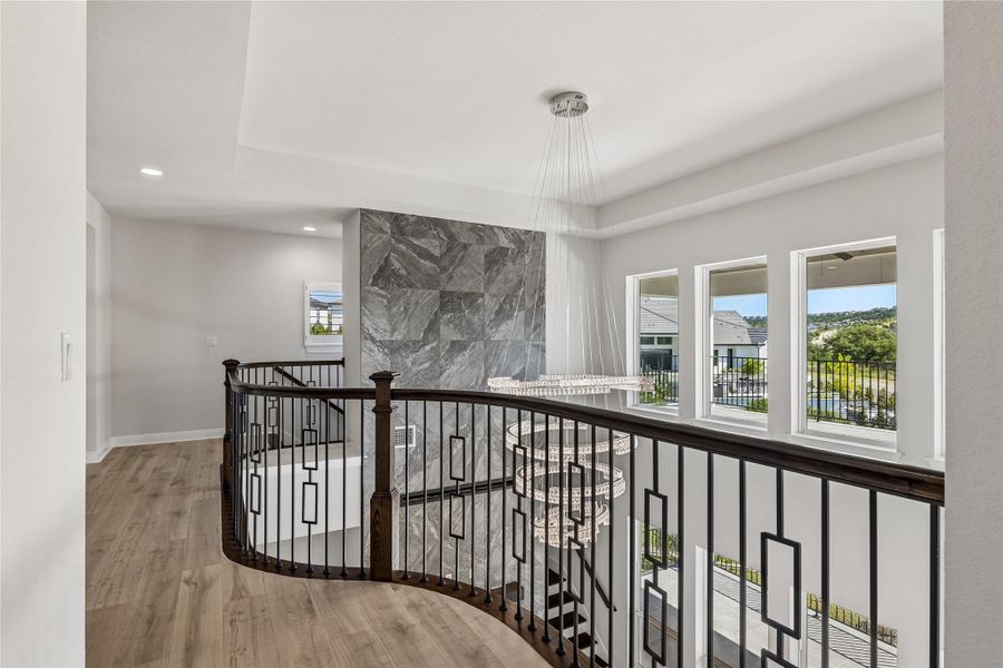 Dramatic two-story foyer showcases a dazzling chandelier and grand staircase with wrought iron balusters.