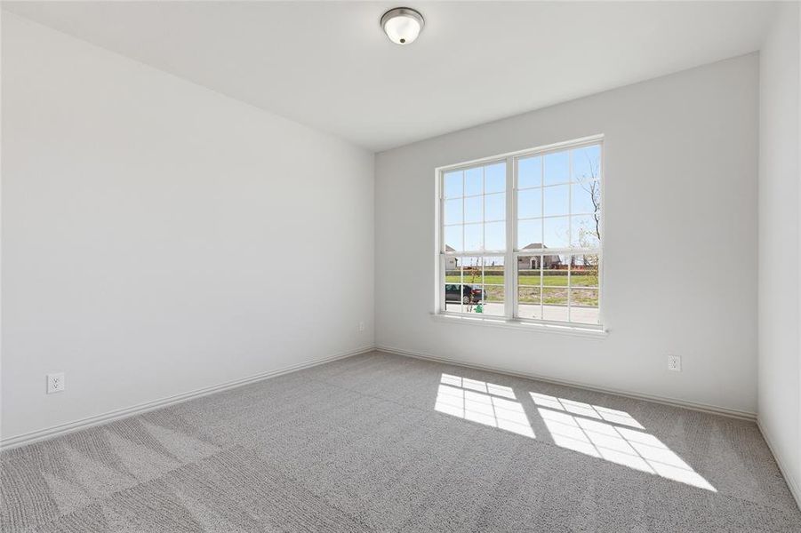 Spacious room featuring neutral paint, gray carpeting, and a multi-pane window with white trim