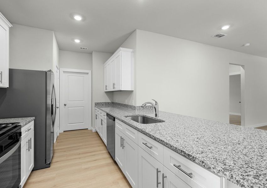 The kitchen has plenty of storage space and a clear view of the living room.