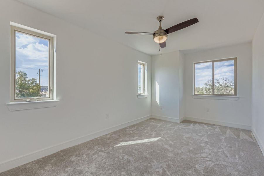 Carpeted empty room with baseboards and a ceiling fan