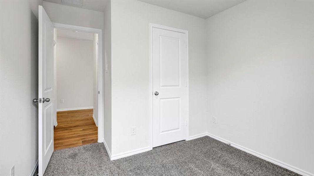 Unfurnished bedroom featuring dark carpet and baseboards