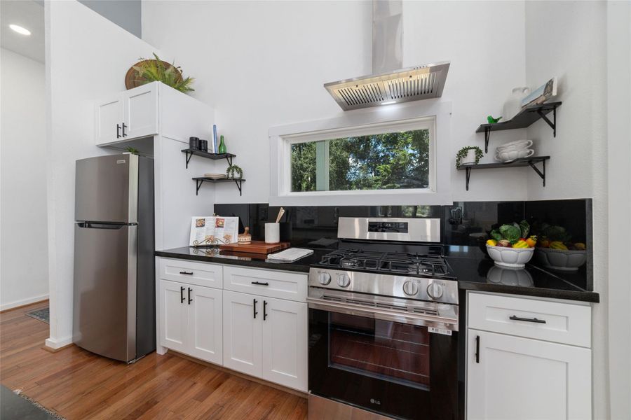 This kitchen features sleek white cabinets, complemented by a stainless steel gas stove and modern range hood. The space is accented with open shelving, creating a bright and inviting atmosphere. This kitchen features sleek white cabinets, complemented by a stainless steel gas stove and modern range hood. The space is accented with open shelving, creating a bright and inviting atmosphere.