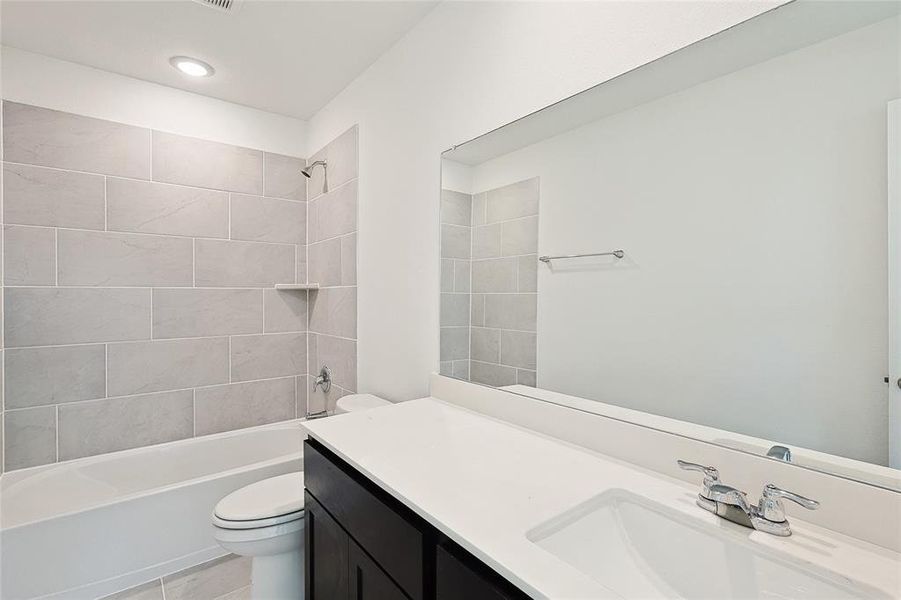 Full bathroom with tiled shower / bath, vanity, toilet, and tile patterned floors