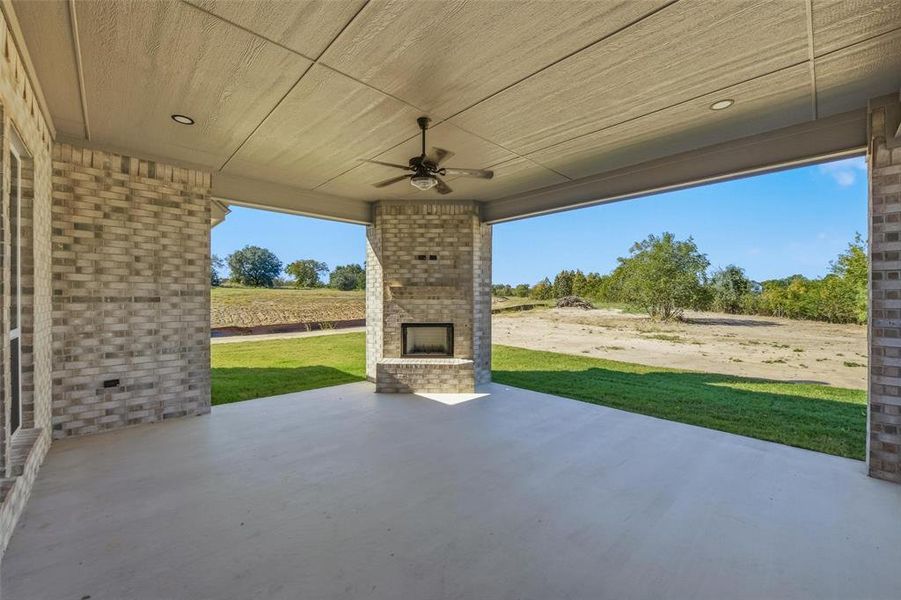 View of patio featuring an outdoor brick fireplace and a ceiling fan