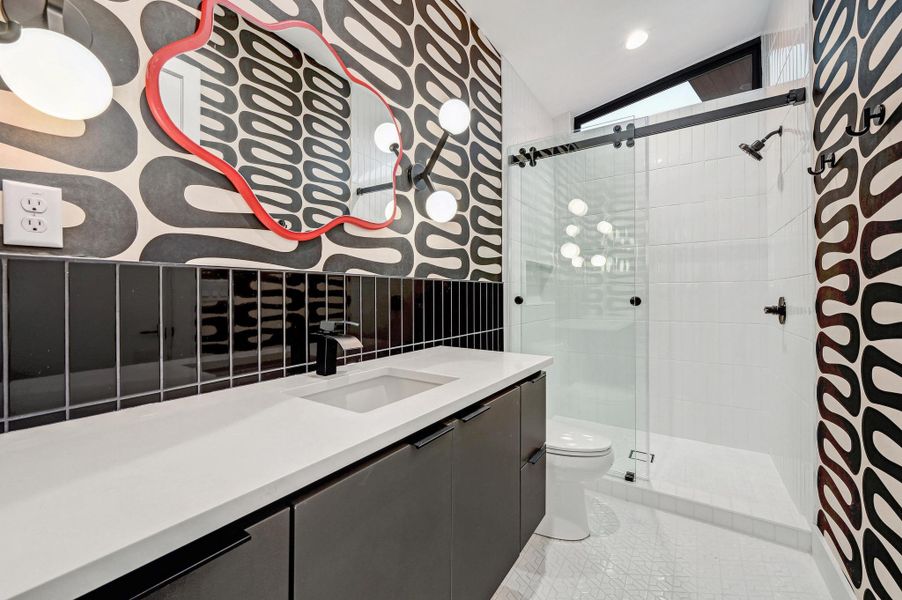 Full bathroom with lofted ceiling, vanity, a shower stall, wallpapered walls, and light tile patterned floors