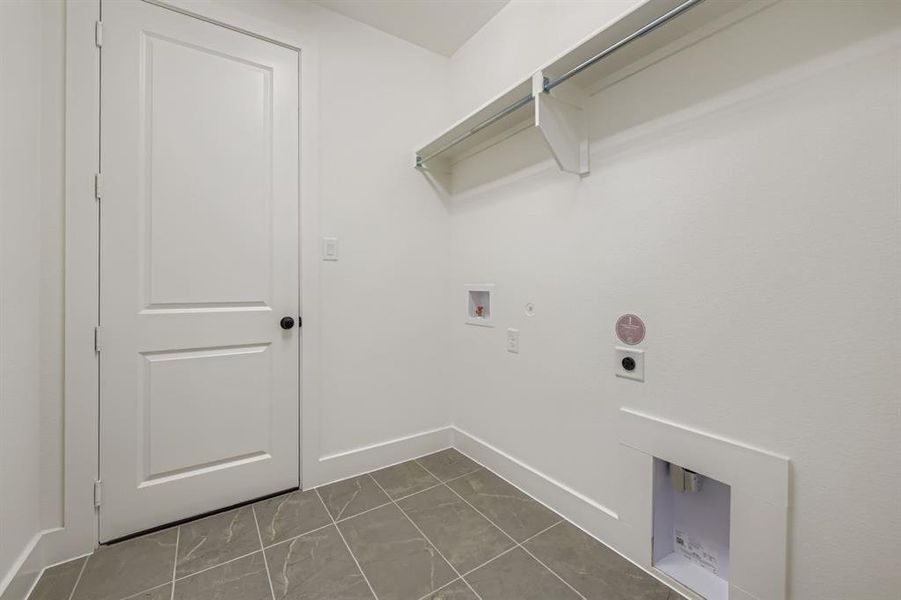 Laundry area with hookup for an electric dryer, hookup for a washing machine, gas dryer hookup, and light tile patterned floors