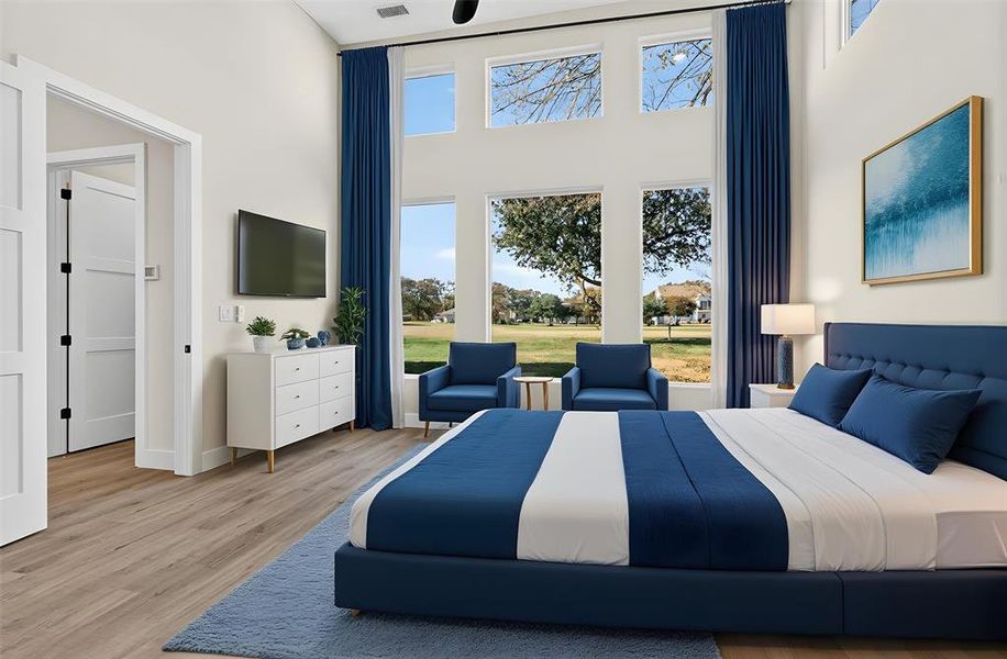 Bedroom featuring multiple windows, wood finished floors, and a high ceiling
