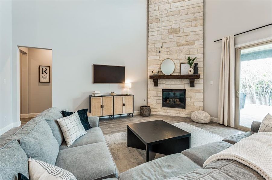 Living room with a stone fireplace, a high ceiling, and hardwood / wood-style flooring