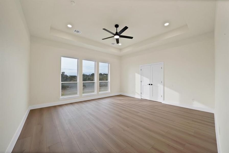 Unfurnished room with light wood-type flooring, a raised ceiling, recessed lighting, and ceiling fan Unfurnished room with light wood-type flooring, a raised ceiling, recessed lighting, and ceiling fan