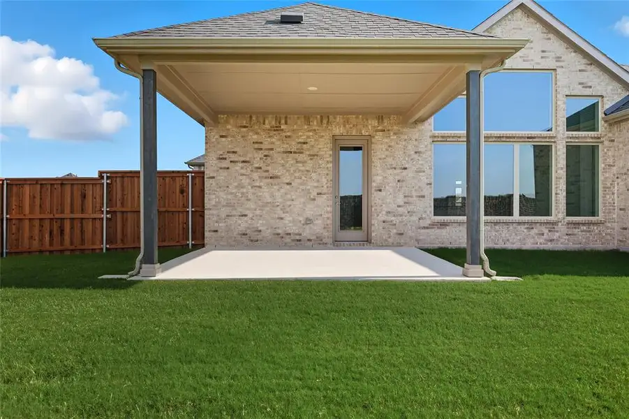 Back of house featuring a patio, brick siding, and roof with shingles