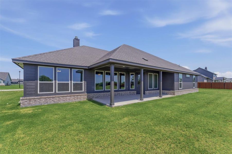 Rear exterior featuring a covered patio, multiple large windows, dark siding, and a stone-clad foundation Rear exterior featuring a covered patio, multiple large windows, dark siding, and a stone-clad foundation