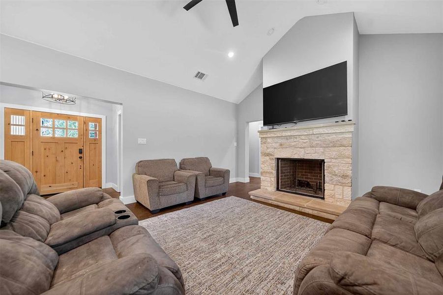 Living room with high vaulted ceiling, wood finished floors, recessed lighting, a fireplace, and a ceiling fan Living room with high vaulted ceiling, wood finished floors, recessed lighting, a fireplace, and a ceiling fan