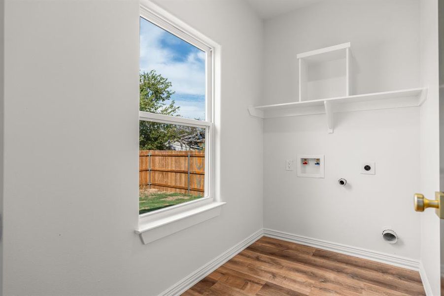 Laundry area featuring hookup for an electric dryer, hookup for a washing machine, and wood finished floors Laundry area featuring hookup for an electric dryer, hookup for a washing machine, and wood finished floors