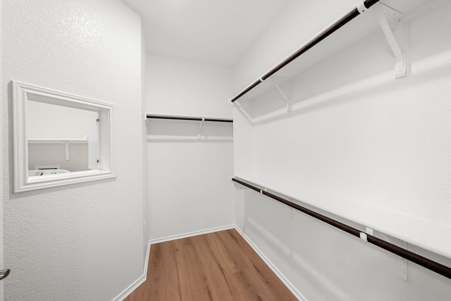 Ample hanging space and shelving define this bright, functional walk-in closet with durable flooring. Ample hanging space and shelving define this bright, functional walk-in closet with durable flooring.