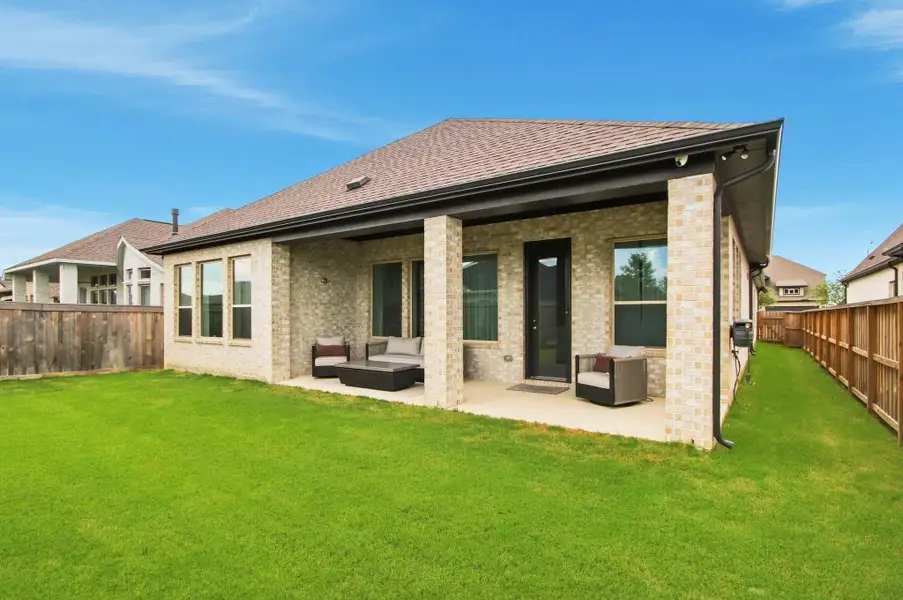 Private backyard retreat featuring a covered patio, expansive lawn, and surrounding privacy fencing.