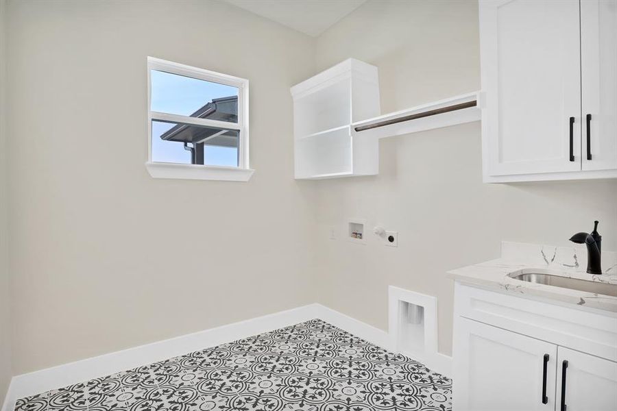 Washroom with sink, light tile patterned floors, electric dryer hookup, hookup for a washing machine, and cabinets