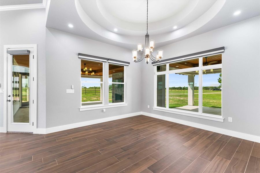 Empty room with plenty of natural light, a chandelier, dark wood finished floors, baseboards, and recessed lighting Empty room with plenty of natural light, a chandelier, dark wood finished floors, baseboards, and recessed lighting