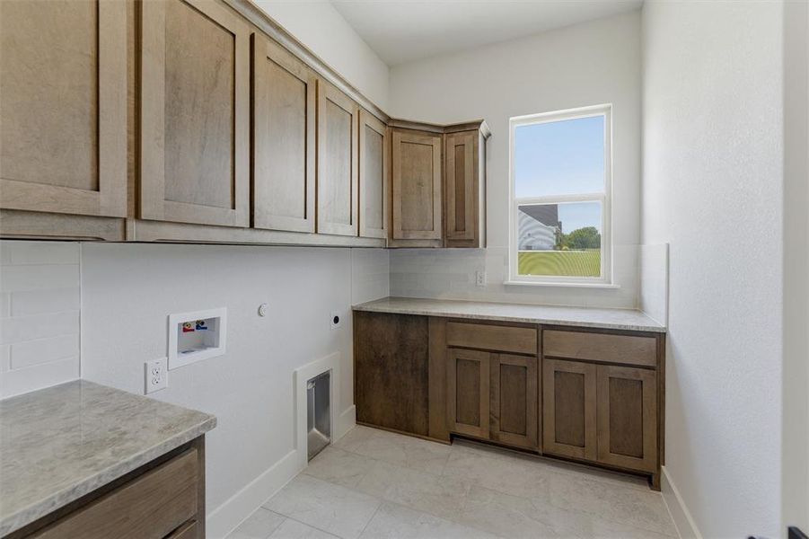 Utility room featuring wood-finish cabinetry, light-toned countertops, subway tile backsplash, and a window