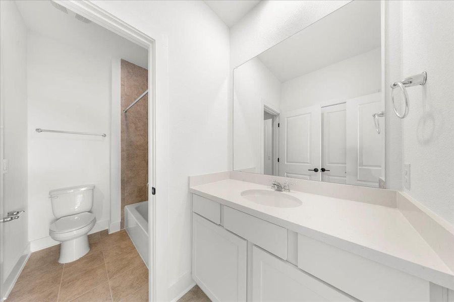 Full bath featuring light tile patterned floors, vanity, and shower combination Full bath featuring light tile patterned floors, vanity, and shower combination