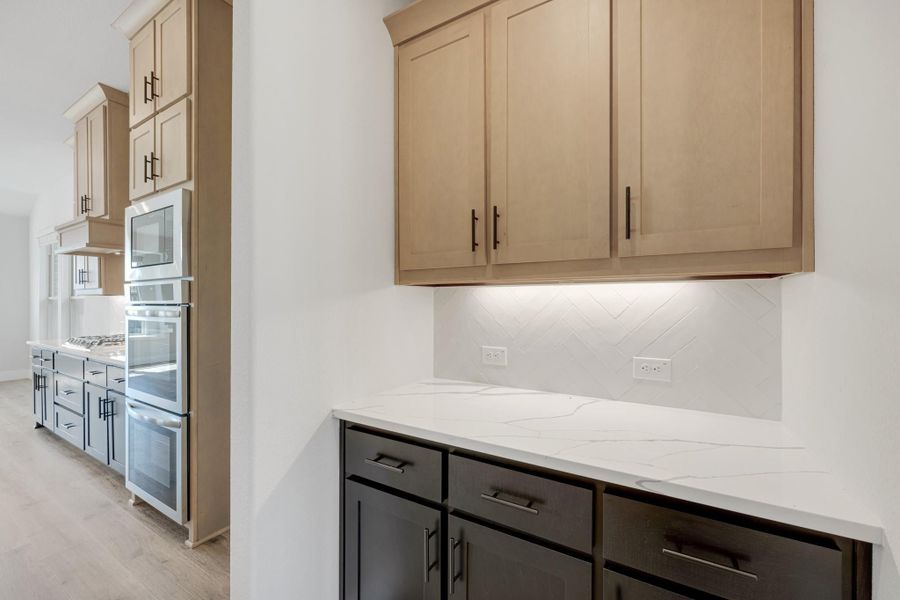 Kitchen with light wood upper cabinets, dark lower cabinets, white quartz countertops, and herringbone tile backsplash Kitchen with light wood upper cabinets, dark lower cabinets, white quartz countertops, and herringbone tile backsplash
