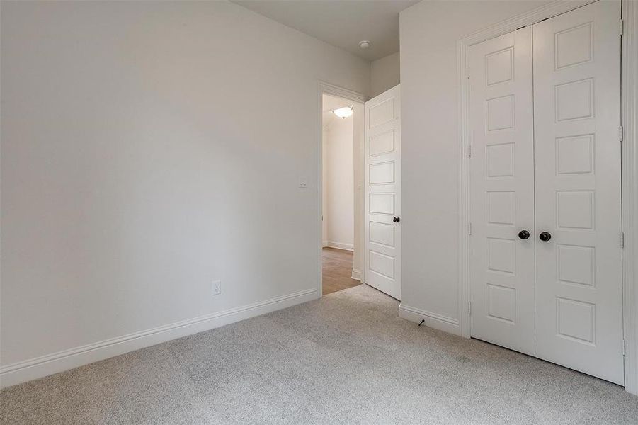 Unfurnished bedroom with light carpet and a closet