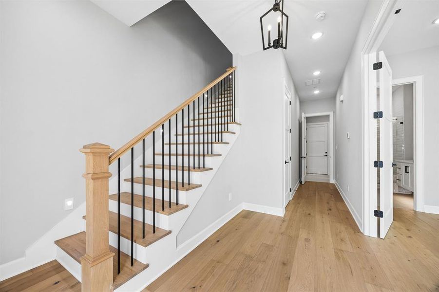 Staircase featuring wood finished floors and hanging lights Staircase featuring wood finished floors and hanging lights