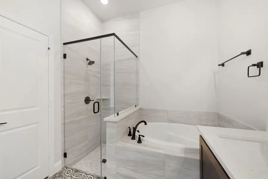 Master bathroom with glass walk-in shower, soaking tub, and gray tile surround with dark bronze fixtures Master bathroom with glass walk-in shower, soaking tub, and gray tile surround with dark bronze fixtures