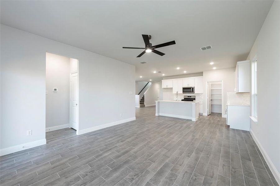 Unfurnished living room featuring ceiling fan, recessed lighting, light wood finished floors, stairs, and baseboards Unfurnished living room featuring ceiling fan, recessed lighting, light wood finished floors, stairs, and baseboards
