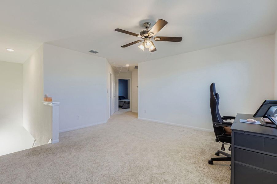 Office featuring light colored carpet, attic access, and a ceiling fan