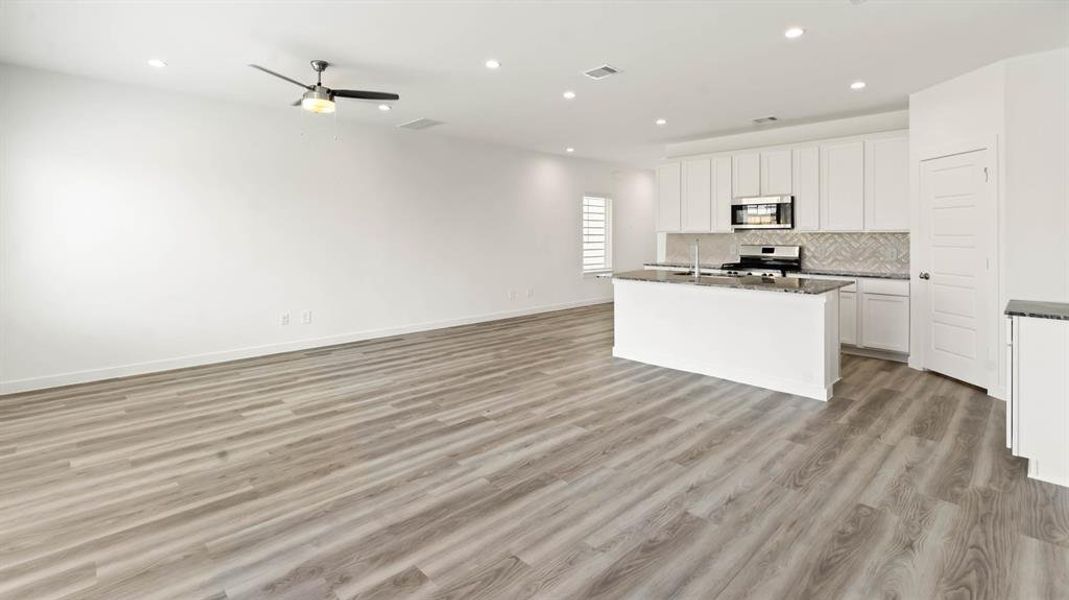 Kitchen with open floor plan, white cabinets, recessed lighting, tasteful backsplash, and light wood-type flooring