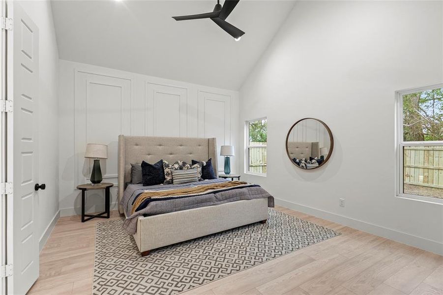 Bedroom with light wood-style flooring, high vaulted ceiling, and baseboards
