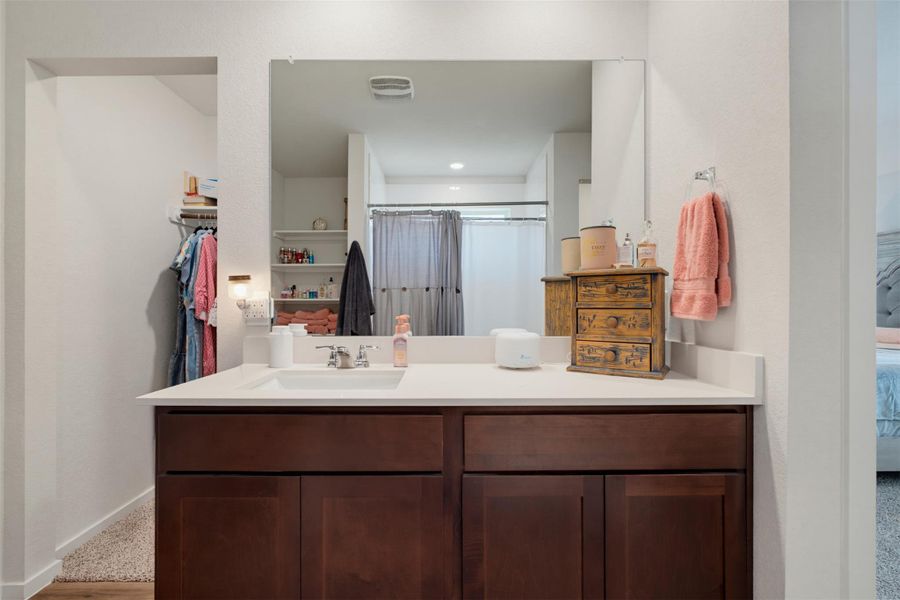 Rich wood cabinetry anchors a contemporary vanity situated next to an open walk-in closet. Rich wood cabinetry anchors a contemporary vanity situated next to an open walk-in closet.