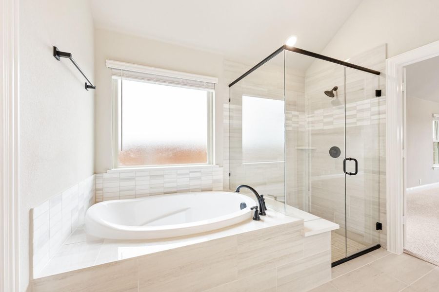 Master bathroom with soaking tub, glass-enclosed shower, white tile, and black fixtures Master bathroom with soaking tub, glass-enclosed shower, white tile, and black fixtures