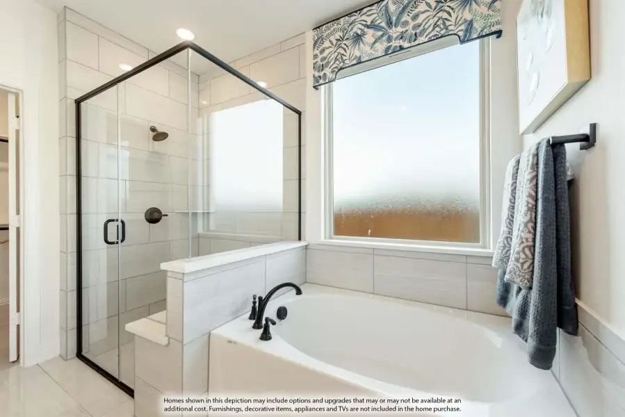 Master bathroom with soaking tub, glass-enclosed shower, gray tile walls, and a frosted window above the tub.