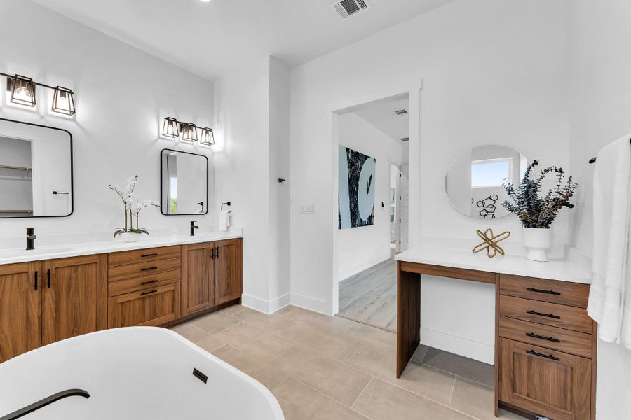 A spacious primary bathroom with a double vanity and a dedicated makeup station provides luxurious comfort. A spacious primary bathroom with a double vanity and a dedicated makeup station provides luxurious comfort.