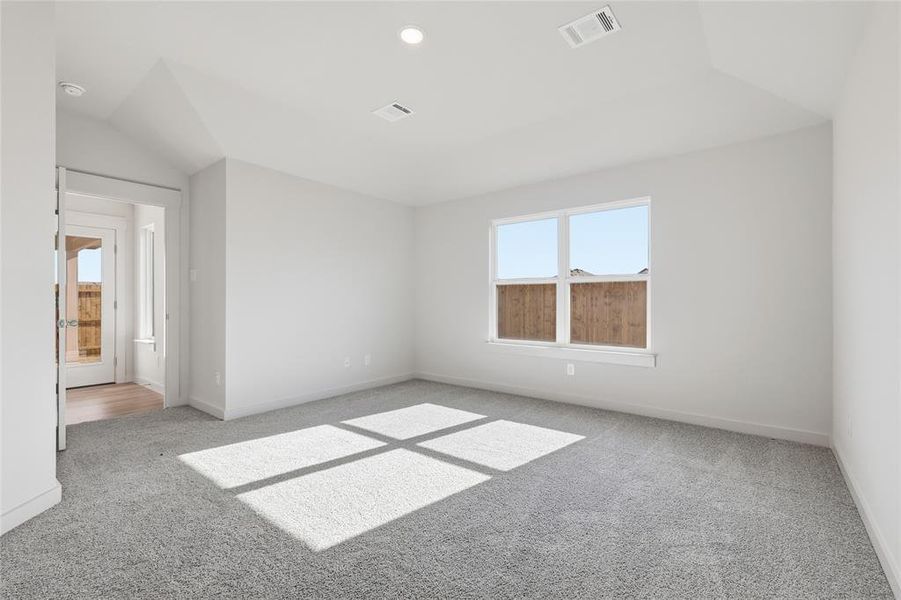 Unfurnished bedroom featuring light carpet and vaulted ceiling