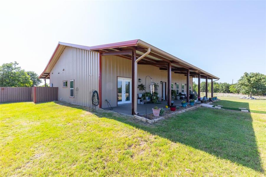 Expansive covered patio extending the length of the structure, featuring a tan metal exterior with a red trim roof Expansive covered patio extending the length of the structure, featuring a tan metal exterior with a red trim roof