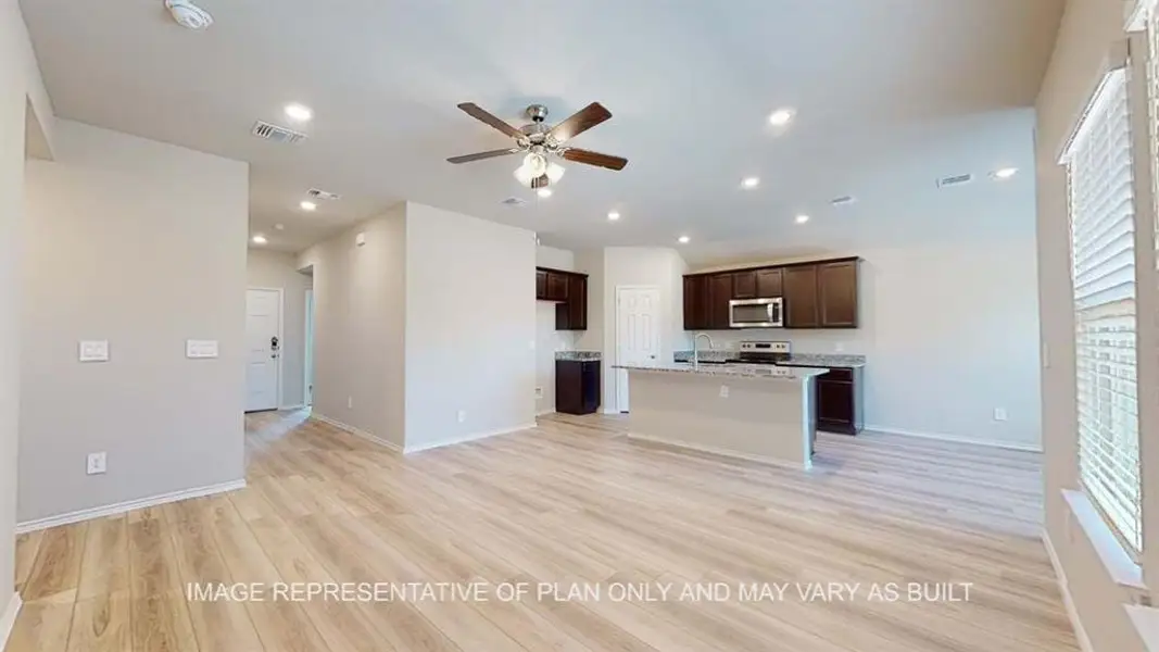 Kitchen with light wood-style flooring, a ceiling fan, dark brown cabinets, open floor plan, and a center island with sink