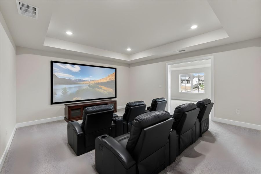 Cinema with a tray ceiling, recessed lighting, and light colored carpet